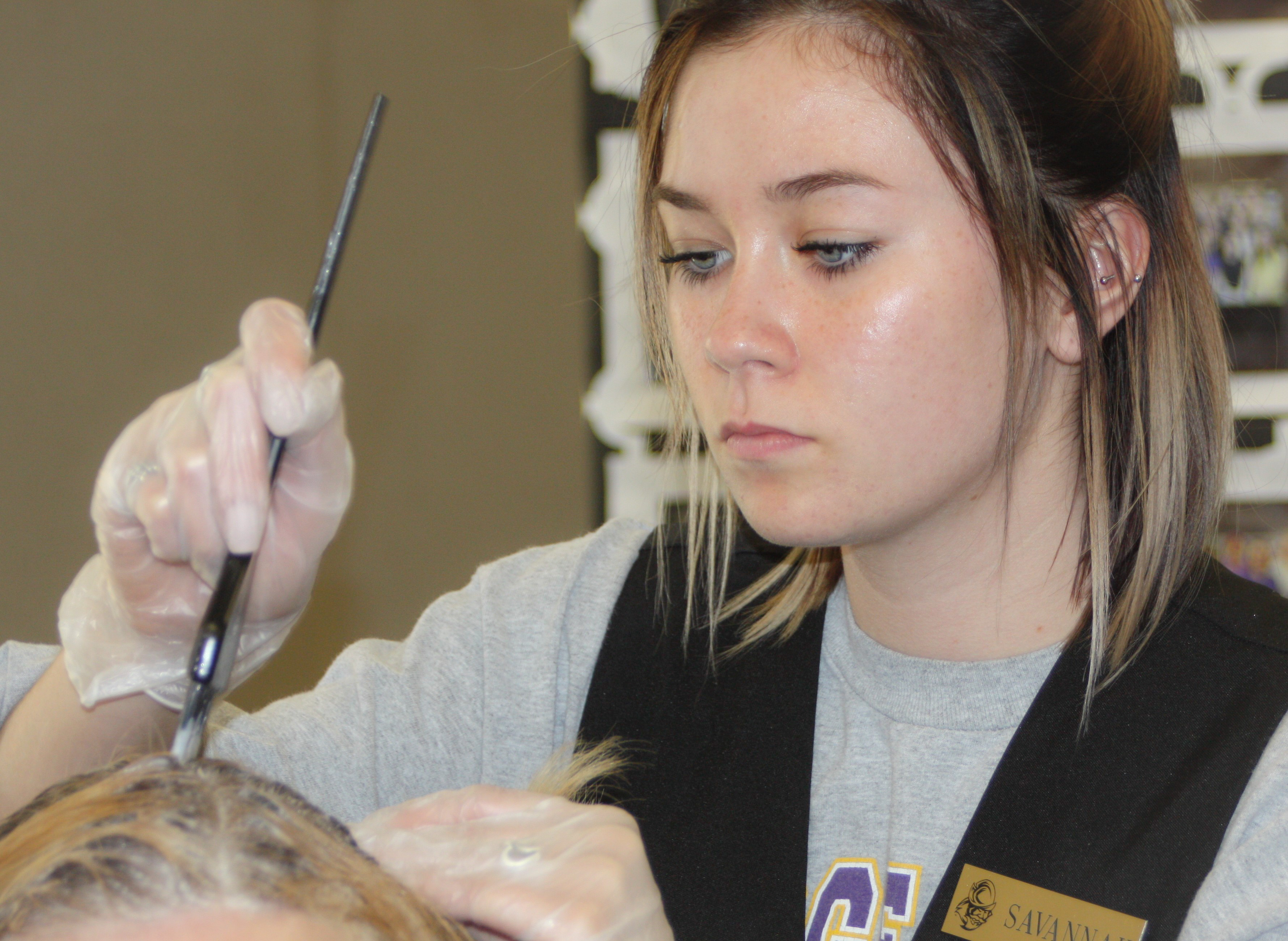 Savannah Shiflet brushing color into a clients hair.