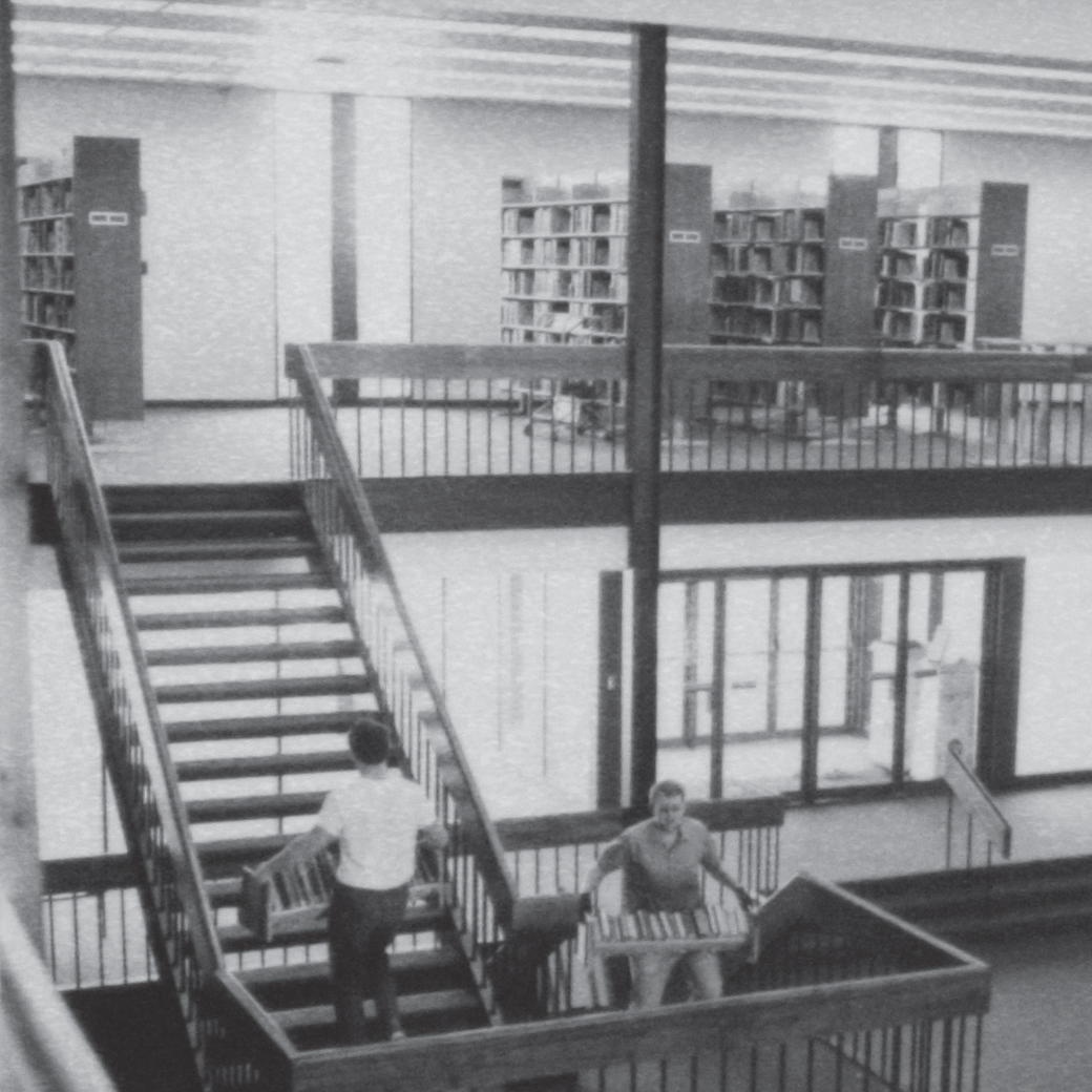 Students carrying books laden with books to the stacks upstairs in the library of the new campus