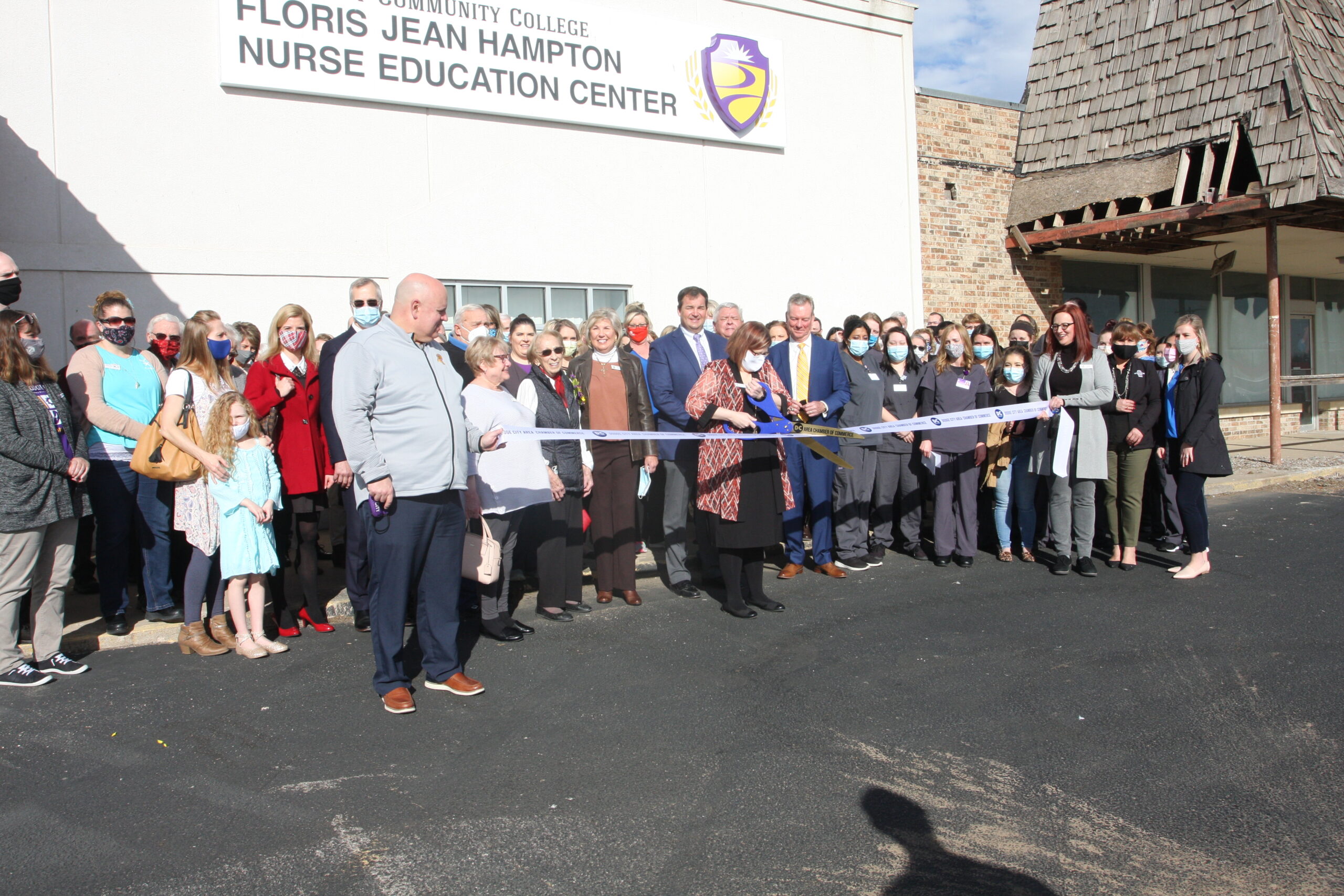 A group of college personnel, family and community members gather for a ribbon cutting outside of the Floris Jean Hampton Nurse Education Center